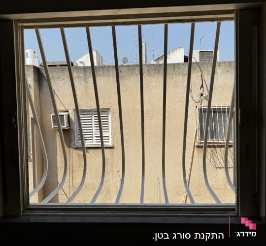 סורגים מתכתיים בחלון עם נוף חיצוני